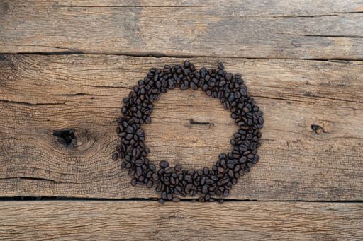 A top view of coffee beans in the shape of a circle on a wooden surface