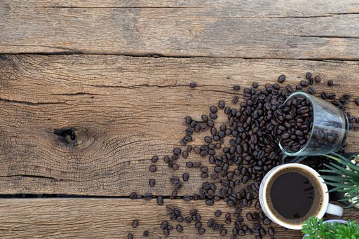 A top view of a cup of coffee and coffee beans on a wooden table
