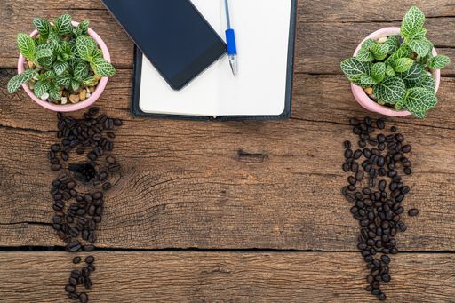 A top view of a notebook with plants and coffee beans on a wooden tab