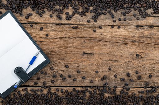 A top view of an open notebook on a table with coffee beans
