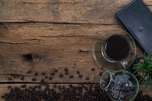 A top view of a smartphone and coffee on a wooden desk