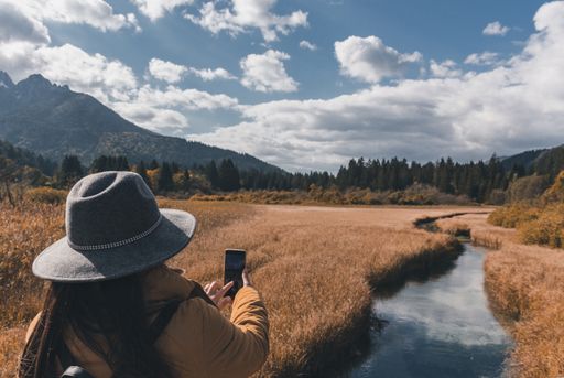 A woman taking photos of autumn landscape at Zelenci nature reserve in Slovenia