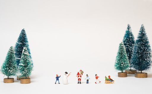 A Christmas scene of miniature figures of Santa Claus and kids playing in the snow
