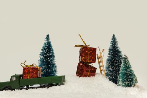 A miniature figure painter painting red gift packages in a snowy area with fir trees