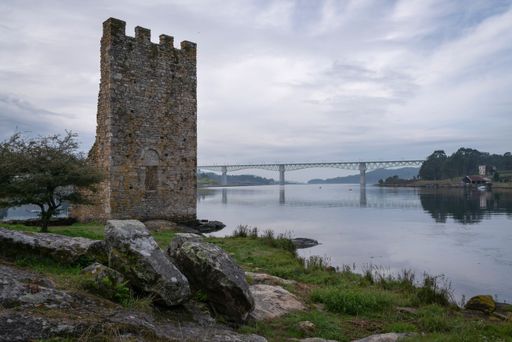 The West Towers in Catoria, Galicia, Spain facing a beautiful river with a bridge.