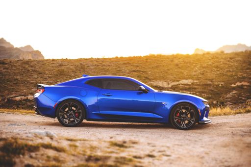 A blue cool powerful muscle coupe sports car parked in the desert at daytime