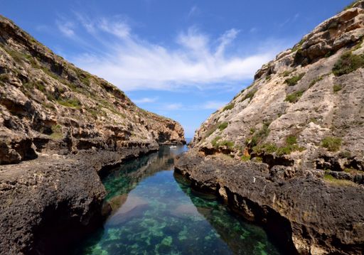 A beautiful view of the clear water surrounded by beautiful cliffs under the blue sky