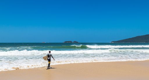 A professional surfer going to the water to surf on the island of Santa Catarina at Mole beach