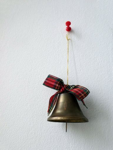 Decorative Christmas bell, tied with a red and green checkered ribbon hanging on the wall