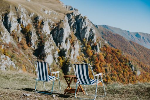 Two beach chairs and a wooden table on the top of a cliff