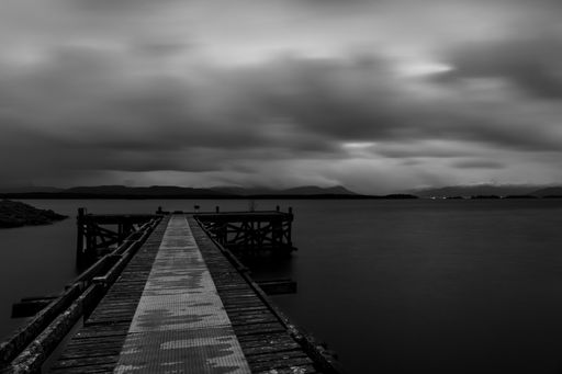 The dramatic cloudy sky over the sea and the wooden pier