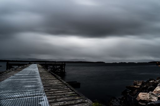 The dramatic cloudy sky over the sea and the wooden pier
