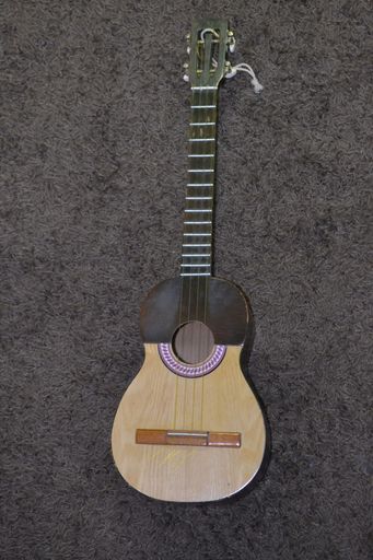 A vertical shot of a guitar on a gray surface