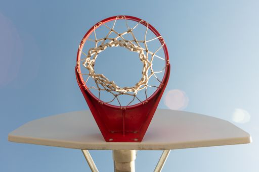 A low angle shot of a basketball hoop against the blue clear sky
