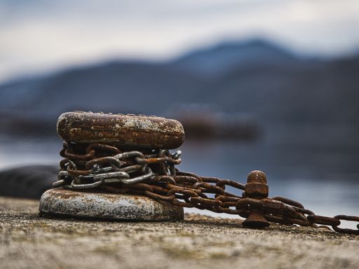 A rusty mooring post with chains by the sea in Omegna, Italy tr