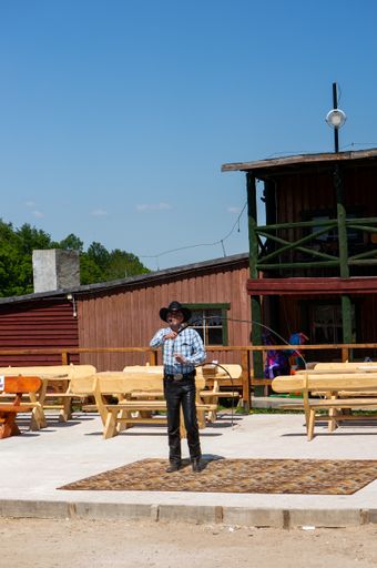 A vertical shot of a cowboy doing tricks with a rope in the Western City park on a sunny day