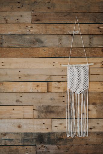 A closeup shot of a white woven wall hanging on a wooden wall