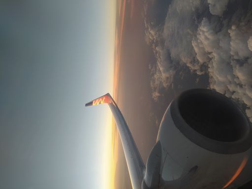 A vertical shot of a sunset from an airplane window