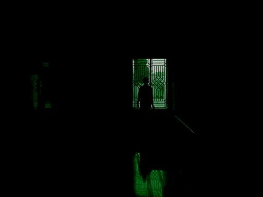 A beautiful shot of a man standing in front of a winow in a dark room