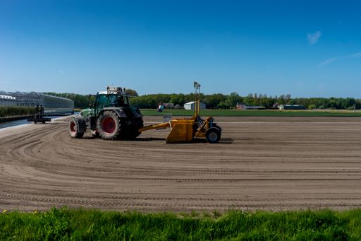 A farmer plowing his field using a tractor on a sunny day in summer