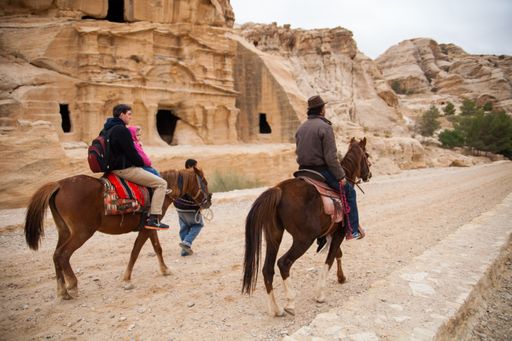 Bedouins of Petra with a tourist on a tour around monuments of Petra while riding horses. Petra, Jordan