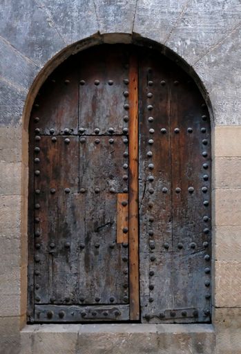 A vertical shot of an old wooden door in the stone wall