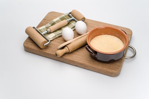 chopping board rolling pin white eggs and terracotta bowl with wholegrain flour on white background with copy space