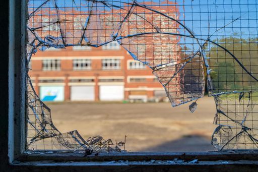 A close-up shot of a broken glass of a window with the view of an orange building