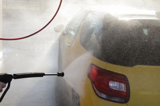 A person washing a black and yellow car in a car wash