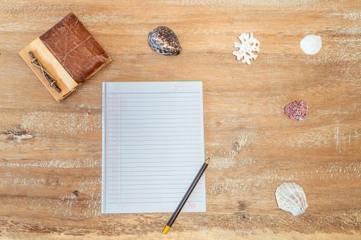 A top view of an open notebook with a pencil on the wooden surface
