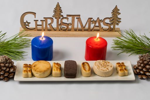 typical christmas sweets on the table decorated with pine cones, pine branches and coloured candles.