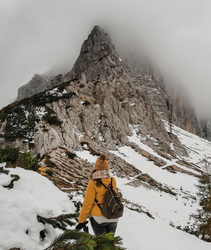 Woman wearing hiking clothes and backpack, walking on snow covered path in mountains. Amazing winter nature in Julia alps in Slovenia.