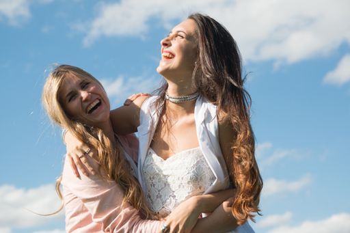 A couple of Argentinian women laughing at each other under a blue sky