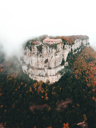 A vertical shot of a foggy day in Spain at Santuario del Far with greenery surrounding it