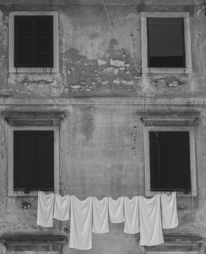 A vertical grayscale of a Croatian old weathered three-story residential building