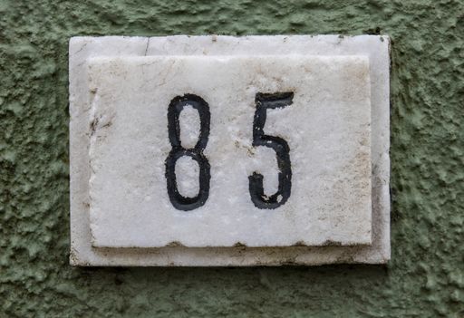 A Closeup of the number 67 on the rustic white wall
