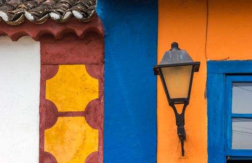 A beautiful old facade, an orange wall with an old street lamp and a blue window