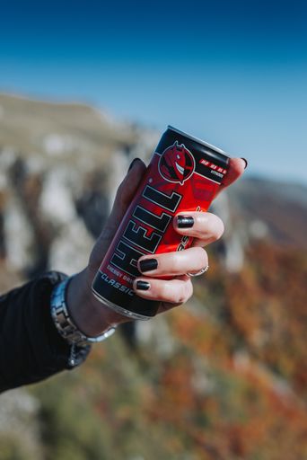 A vertical shot of a person holding a Hell energizer coffee