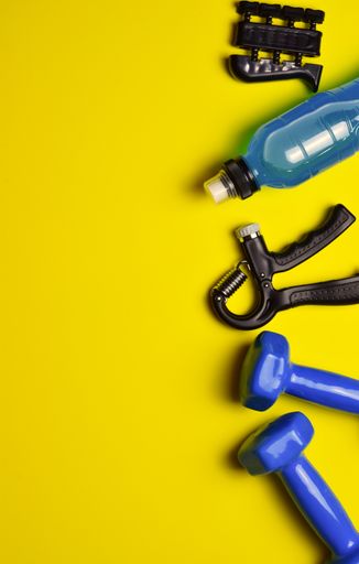 A top view of fitness related items on a yellow background with a copy space