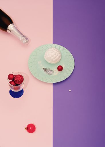 A vertical shot of Christmas champagne, plate, and glass with decorations on a pastel background