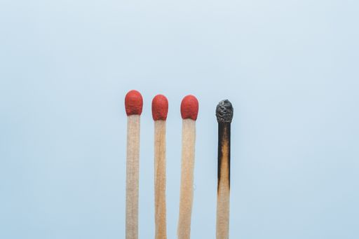 A closeup of four matches and a used one aligned with isolated blue background