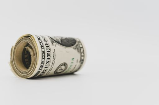 US dollar banknotes rolled up on a white tabletop with text space
