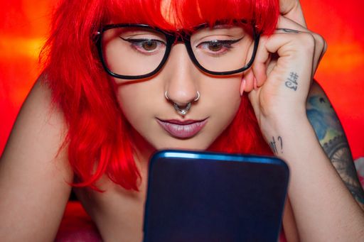 A closeup shot of a red-haired female looking at her smartphone