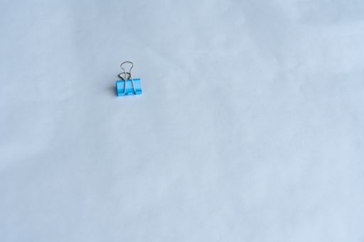 A closeup shot of a blue binder clip on a blue background