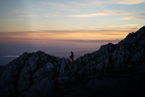 A man walking at the top of the mountain during sunset