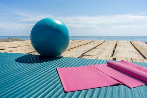 An exercise mat and ball on a wooden surface near a coast
