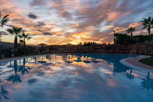 A beautiful calm scene of a pool in a residential recreation area with reflected sunset