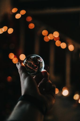 A vertical shot of a person holding a crystal ball with a bokeh background