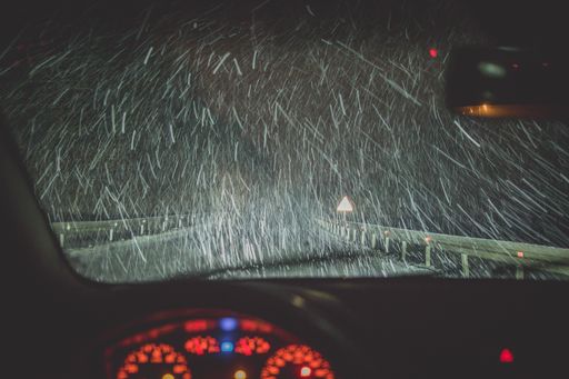 A highway on a snowy day shot from a car at nighttime