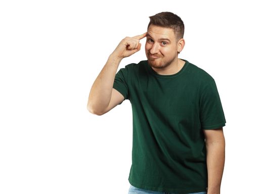 A young smart bearded Caucasian man pointing his index finger on his head for having a good idea
